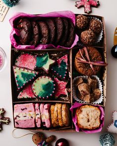 an open box filled with different types of cookies and pastries on top of a table