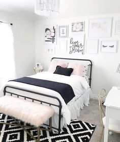 a white and black bedroom with pictures on the wall above the bed, pink fluffy rug