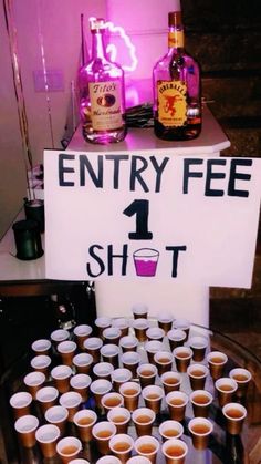 there is a sign that says entry fee 1 shot on the table with cups in front of it