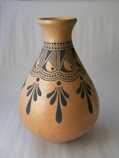 a brown and black vase sitting on top of a white table