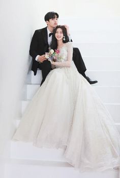 a man and woman in formal wear sitting on some stairs