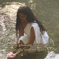 a woman kneeling in the water holding a flower