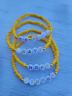 three beaded bracelets with words that spell brave, hope and strong on them