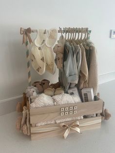 a wooden crate filled with lots of baby clothes and hats on top of a table