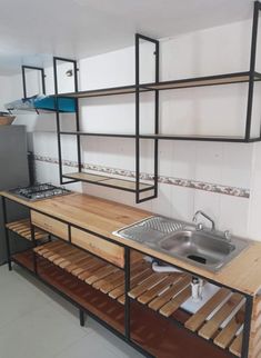 a kitchen area with a sink, refrigerator and shelving unit in the middle of it