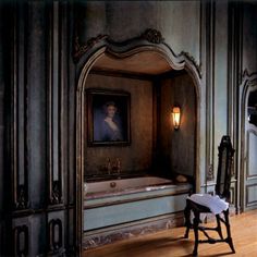 an old fashioned bathtub in a room with wood flooring and ornately decorated walls