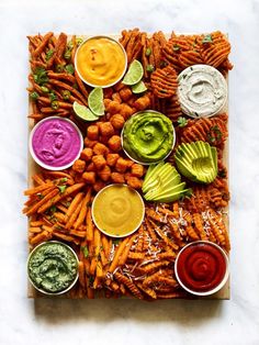 a platter filled with different types of dips and veggies next to dipping sauces