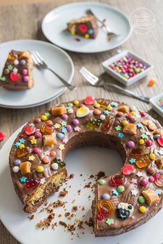 a large chocolate cake with sprinkles on it sitting on a table next to plates and utensils