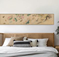 a bed with white sheets and pillows on top of it next to a wall painting