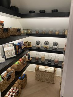 an organized pantry with lots of food items on the shelves and wicker baskets in front of it