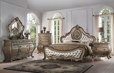 a bedroom with white walls and wooden flooring, an antique style bed has ornate carvings on the headboard