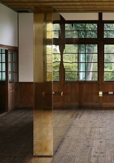 an empty room with wooden floors and large windows in the center, surrounded by wood paneling