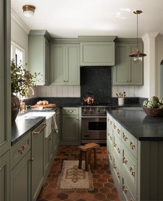 a kitchen with green cabinets and black counter tops, along with an area rug on the floor