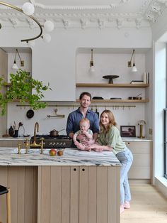 a man, woman and child are sitting on the kitchen counter with an island in front of them