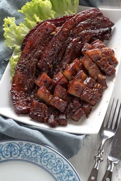 a plate with meat and lettuce on it next to a knife and fork