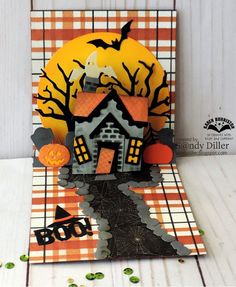 a halloween card with a house and pumpkins