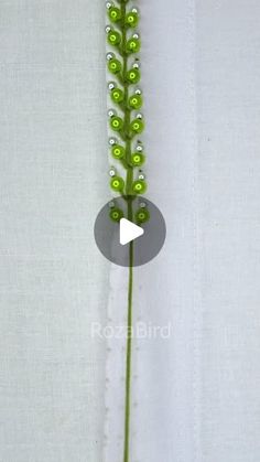 a close up of a green flower on a white cloth with an arrow in the middle