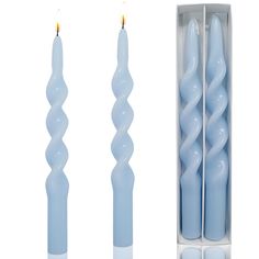 two blue candles are in a box and one is white with a single candle sticking out of it