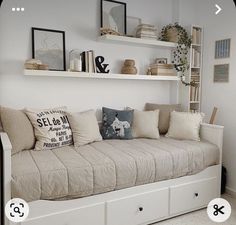 a living room with white walls and shelves filled with pillows, bookshelves and other items