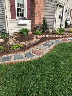 a stone walkway in front of a house with grass and flowers on the side walk