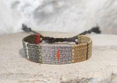 a close up of a bracelet on top of a white rock with an orange stripe