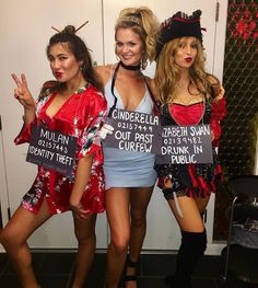 three women dressed up in costumes posing for the camera with signs on their shoulders and feet