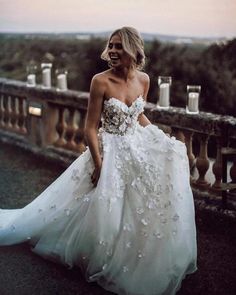 a woman in a white wedding dress is walking down the street with her hand on her hip