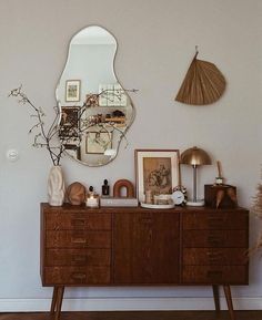 a wooden dresser sitting next to a mirror on top of a wall