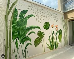 a mural on the side of a building with green plants and flowers painted on it