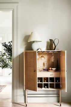 a wooden cabinet with wine bottles on top and a lamp above it in a living room