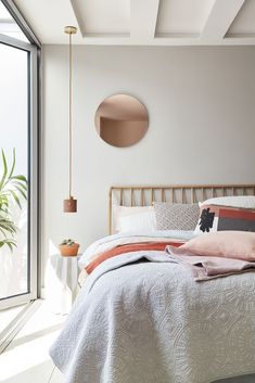 a bedroom with a bed, mirror and potted plant