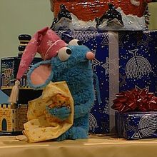 a blue stuffed animal sitting next to two wrapped presents