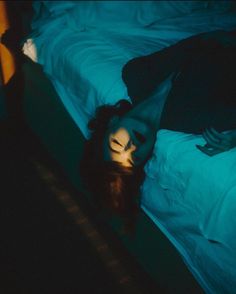 a woman laying on top of a bed in a dark room