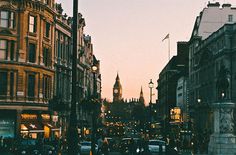 a city street filled with lots of traffic and tall buildings at sunset or dawn in the background