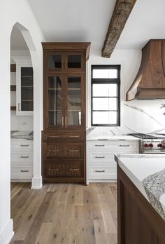 an empty kitchen with wooden cabinets and marble counter tops, along with hardwood flooring