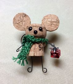 a wooden mouse with a green scarf around it's neck holding a red gift