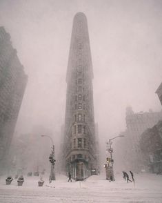 people are walking in the snow near a tall building