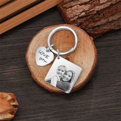 a keychain with two pictures on it and the words love you written in silver