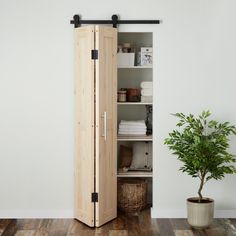 a tall wooden cabinet sitting on top of a hard wood floor next to a potted plant