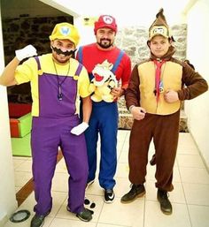 three men dressed in costumes standing next to each other on a tile floor with one man wearing a mario costume