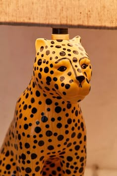 a yellow and black leopard figurine sitting on top of a wooden table next to a lamp