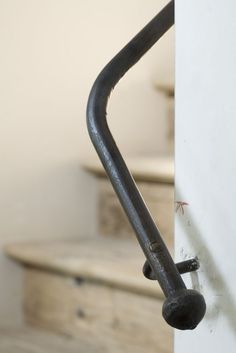 a black and white photo of a metal pipe on the wall next to a toilet