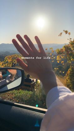 someone is holding their hand out to take a picture in the rear view mirror while driving