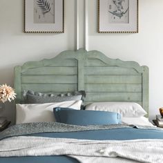 a bed with two pictures above it and a blue blanket on the headboard,