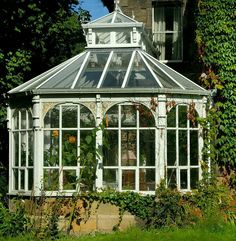 an old white victorian style glass house in the garden