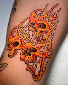 a man's arm with flames on it and two skulls in the middle of his arm