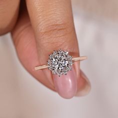 a woman's hand with a diamond ring on top of her finger and the other hand holding an engagement ring