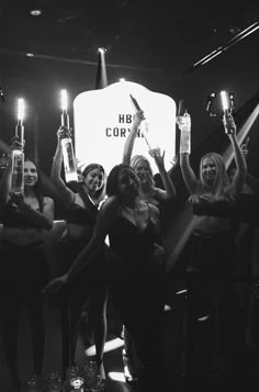 a group of women standing around each other holding up bottles with candles in their hands