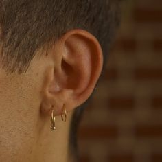 a close up of a person wearing gold earring and looking at the side of their face