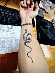 a person's arm with a snake tattoo on it, next to a keyboard